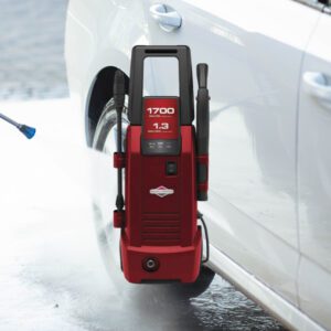 A red and black pressure washer is on the side of a white car.