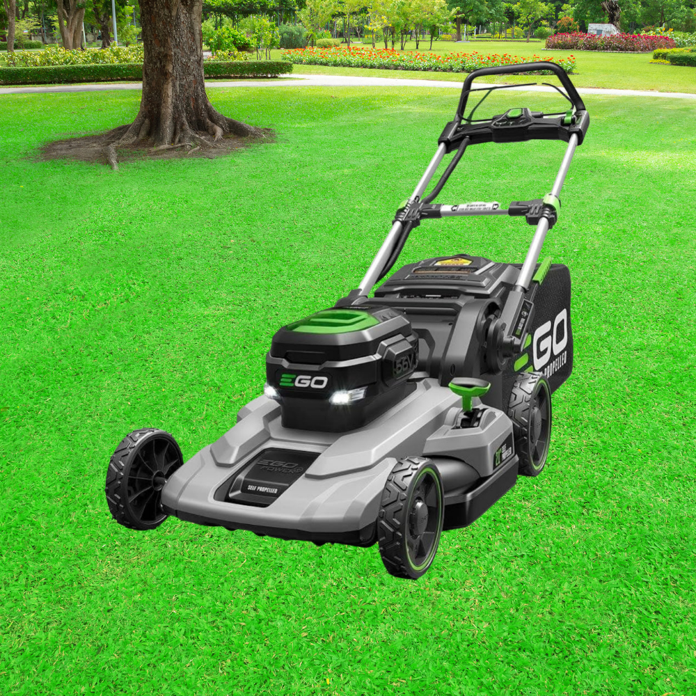 A lawn mower sitting in the grass near a tree.