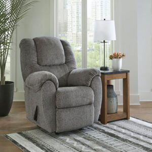A gray recliner sitting in front of a window.